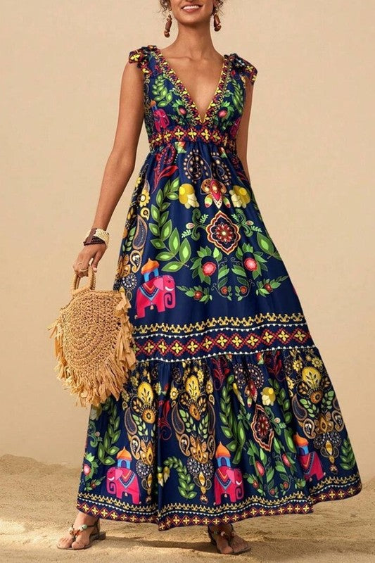 Bold, vibrant, and full of spirit — the Boho Bloom Maxi is made for making memories under the sun.

Featuring a deep V neckline, playful shoulder ruffles, and a flattering empire waist, this dress flows into a tiered skirt adorned with an eclectic mix of florals, paisleys, and whimsical elephants.

Its rich navy base brings out the bright jewel-toned motifs, giving it a striking folkloric charm.

Lightweight and eye-catching, it’s perfect for sun-drenched strolls, weekend markets, or destination adventures.