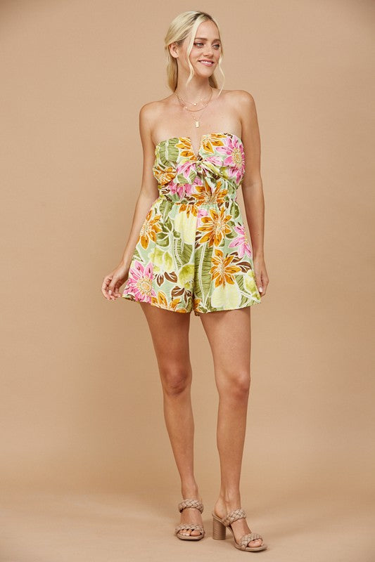 Embrace tropical vibes with our vibrant strapless romper, designed to bring a touch of island paradise to your wardrobe.

V trim tie front tube top romper with lined shorts.

Featuring a lush floral print in shades of yellow, orange, pink, and brown, this romper is perfect for sunny days and summer getaways. The strapless design accentuates your shoulders, while the elasticated waist ensures a comfortable and flattering fit.