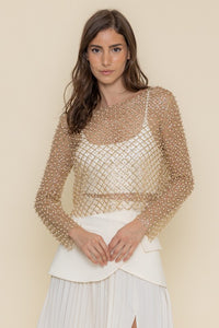 Turn heads with this stunning sheer top adorned with intricate pearl detailing.

The delicate beading creates a mesmerizing geometric pattern that adds a touch of luxury and elegance to any outfit. With its long sleeves and sheer material, this piece is perfect for layering over a neutral camisole for a sophisticated look.

Pair it with a sleek skirt or tailored pants for an effortlessly chic ensemble that transitions seamlessly from day to night.