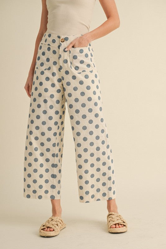 Bring playful charm to your wardrobe with the Polka Breeze Wide-Leg Pants. Featuring a cream base with soft blue polka dots, these pants offer a relaxed, cropped silhouette perfect for casual days.

Designed with front and back patch pockets, a button closure, and an elasticized back waistband for extra comfort, they combine style and ease effortlessly.

Pair them with a simple tank or blouse for a chic, laid-back look.
